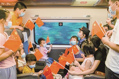 2020年10月5日，國慶長假第五天，在深圳北至九江G634次高鐵列車上，列車工作人員和旅客手拿國旗歡慶國慶。  鮑贛生 攝