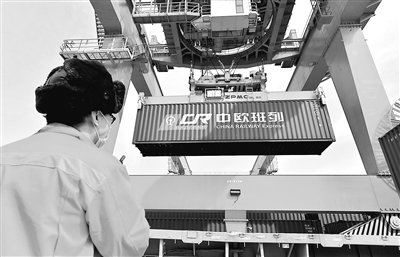 3月11日，一列滿載服裝、電子配件、電器等50車貨品的列車駛出西安新筑車站，開(kāi)往德國(guó)曼海姆，標(biāo)志著2020年中歐班列（西安）去程班列發(fā)送車數(shù)突破1萬(wàn)車。圖為工人在西安新筑車站貨場(chǎng)指揮吊運(yùn)中歐班列集裝箱。 新華社發(fā)（唐振江 攝）