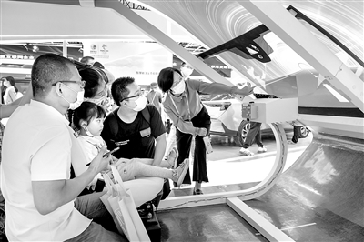 圖為在第三屆數(shù)字中國建設峰會期間，福耀集團展區(qū)展出的最新的車載智能投屏玻璃吸引不少觀眾。圖為幾名觀眾在工作人員講解下現(xiàn)場體驗。 魏影 攝