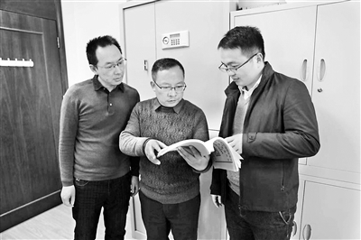 圖為韓錫才(中)正在與同事們研究相關(guān)案情。尹琦琦 攝