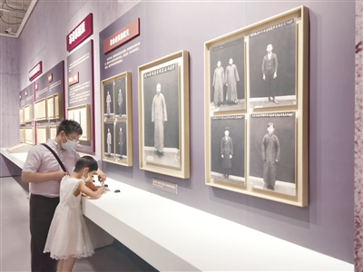 圖為“民族復(fù)興的百年旗幟——中國歷史研究院征集海外中共珍稀文獻(xiàn)展”現(xiàn)場(chǎng)，小觀眾在革命先烈遺照前寫下參觀感言。  本報(bào)記者 聶新鑫 攝